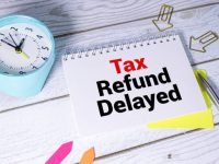 Sticky note with the text Tax Refund Delayed on Income Tax form background with calculator