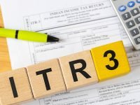 Indian taxes. An Indian income tax form on a desk with a calculator and pen, and wooden blocks with the symbol ITR-3. The financial concept of India
